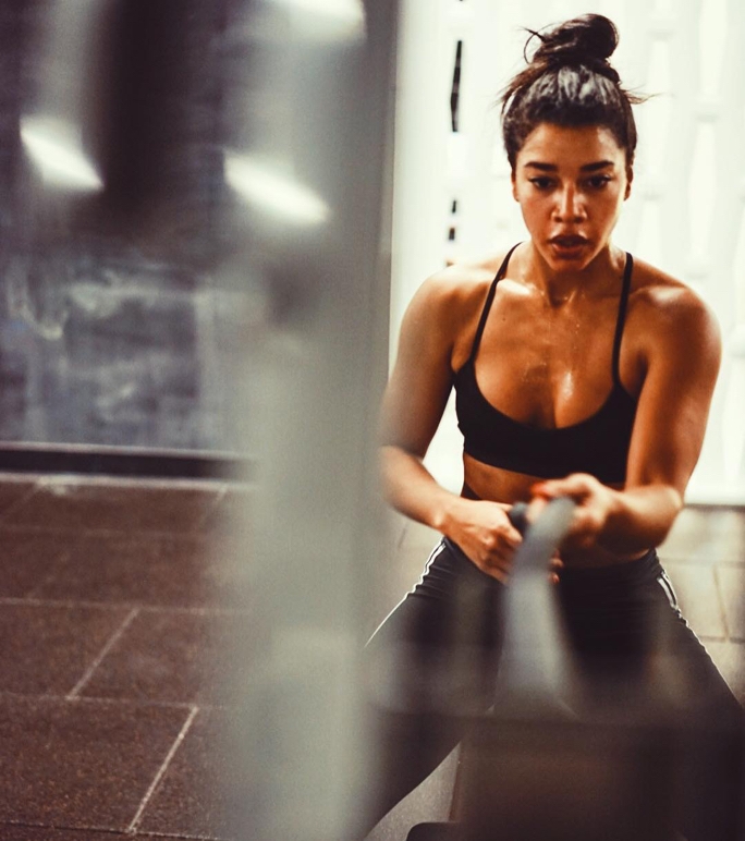 A face-on shot of Hannah Bronfman pulling a rope while circuit training