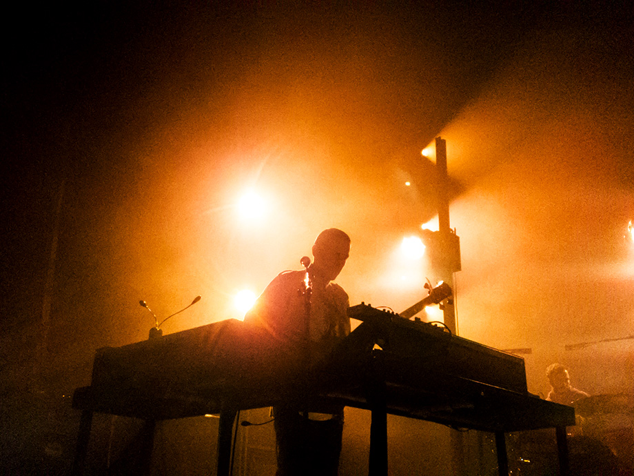 Musician on stage with orange backlight.