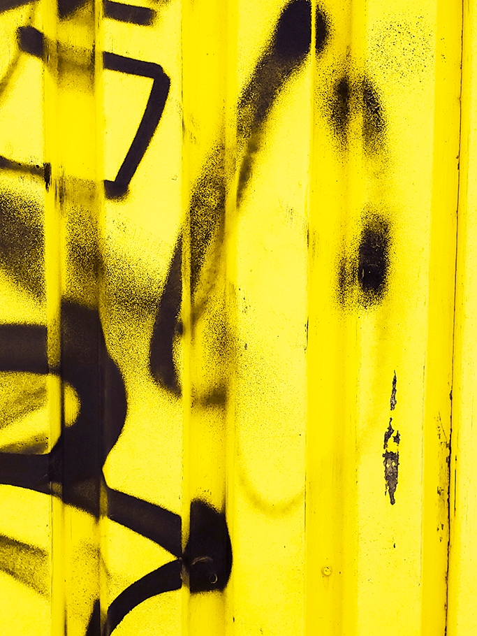 Black spray paint on yellow wall.