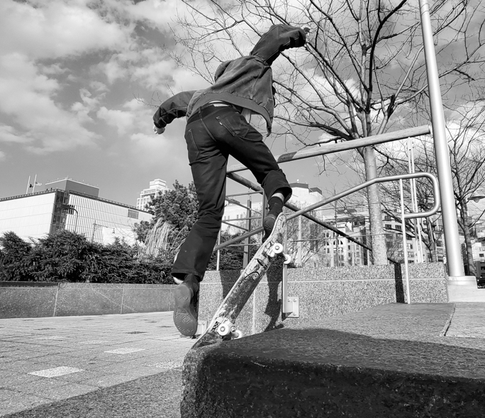 Man practicing tricks on skateboard using a stair railing