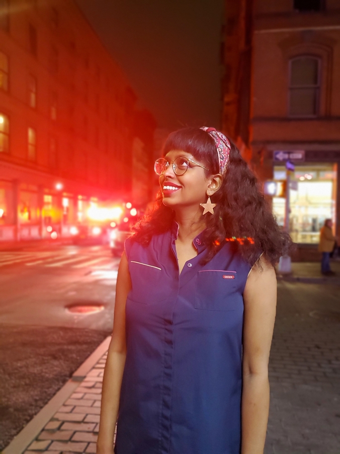 Woman standing on the sidewalk gazing up as bokeh lights shine in the background