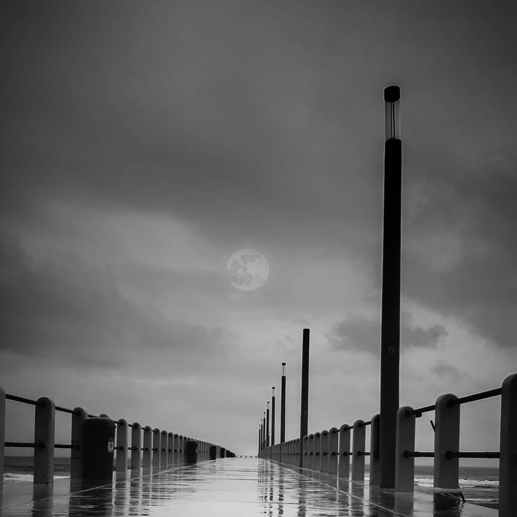 Moon behind fog above water.