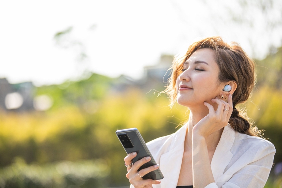 Image of woman outside listening to music with headphones on to tune into mindfulness