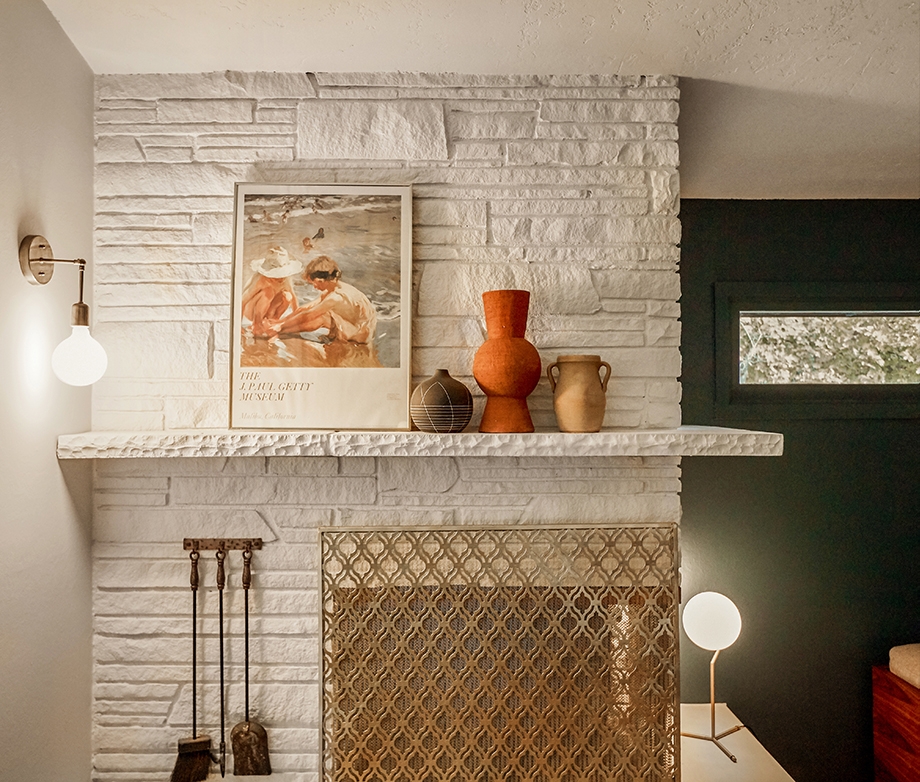 There are three sculptures and one work of art on a shelf against a white wall. They are showing Kirsten Grove's interior wall design.