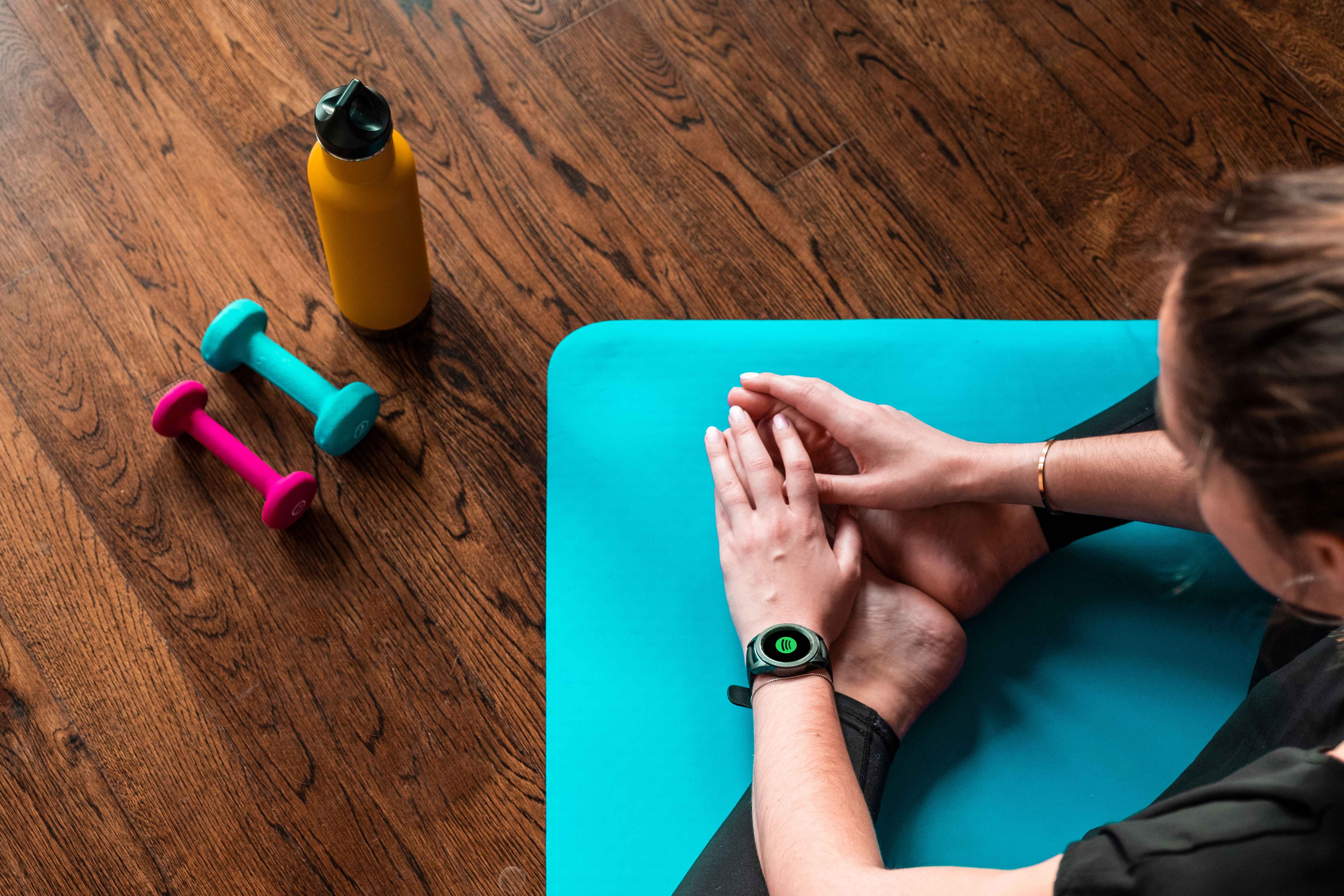 Woman stretching while wearing Galaxy Watch that shows Spotify pairing