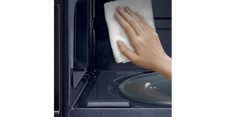 Person using cloth to clean inside of a Samsung Microwave