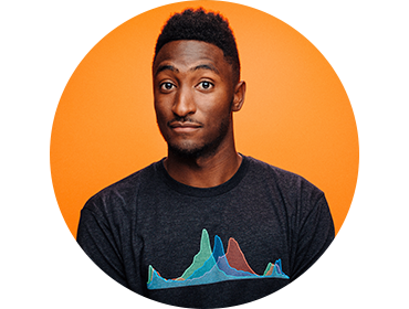 Headshot of Marques Brownlee against an orange background. He's wearing a T-shirt and ginning slightly with his eyebrows raised