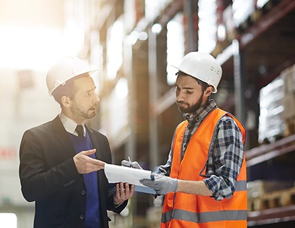 Two men in hard hats reviewing paperwork