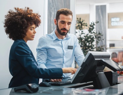 Two retail employees standing infront of a point of sale terminal