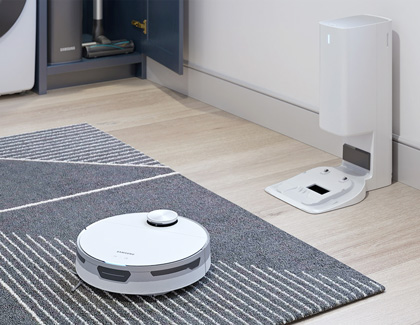 Samsung Jet Bot Robot cleaning a rug with the charging station nearby