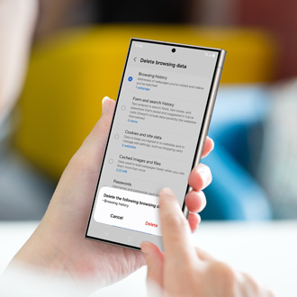 Hand holding a Galaxy phone displaying the 'Delete browsing data' menu, with options for browsing history, cookies, and cache