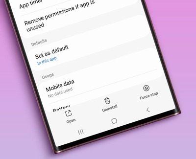 Close-up view of a Galaxy phone screen displaying app settings, highlighting options like 'Mobile data', 'Open', 'Uninstall', and 'Force stop'. The background indicates the settings for app permissions and defaults.