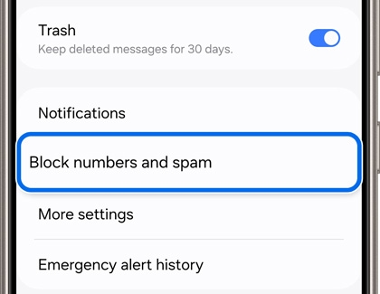 Galaxy phone screen displaying the messaging settings menu. Highlighted is the option 'Block numbers and spam', with other menu items including 'Trash', 'Notifications', 'More settings', and 'Emergency alert history'.