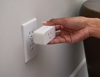 Woman inserting smart plug into the wall socket