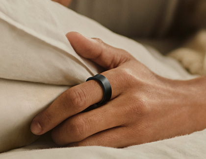 A close-up of a hand wearing a Samsung Galaxy Ring while resting on a pillow.