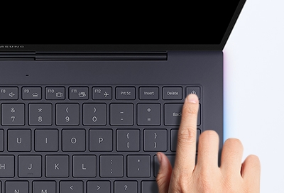 A Samsung Galaxy book with a person pressing the power button