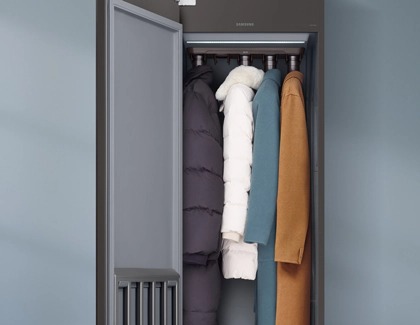 Samsung AirDresser with the door open, holding several winter coats and jackets inside.