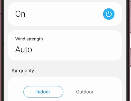 A Samsung phone screen displaying SmartThings controls for an air purifier, showing power status, wind strength set to Auto, and air quality options for Indoor and Outdoor.