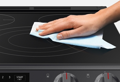 Woman wiping Samsung electric cooktop with a cloth