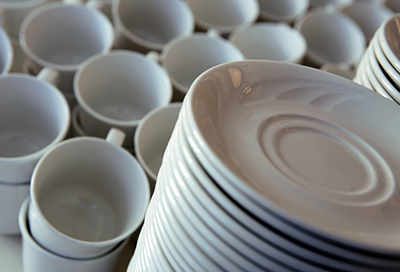 Stacks of white ceramic dishes and cups on a countertop