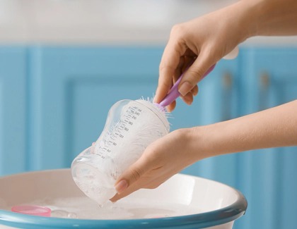 Woman brushing the inside of a baby bottle