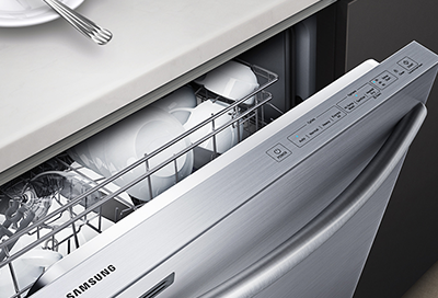 A Samsung dishwasher loaded with plates and cups, with the door ajar