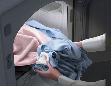 A person placing clothes into a Samsung dryer.