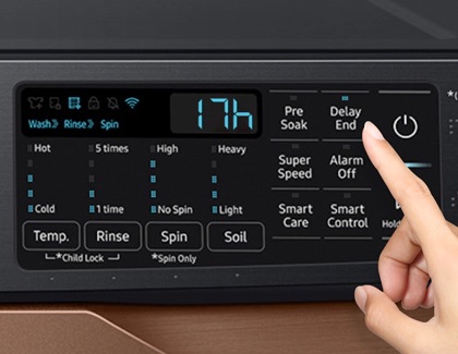 A finger tapping a button on the control panel of a Samsung washing machine.
