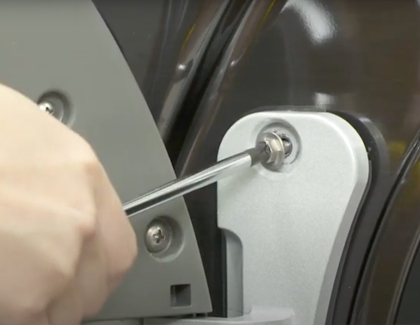 Person removing a door hinge screw from Samsung dryer
