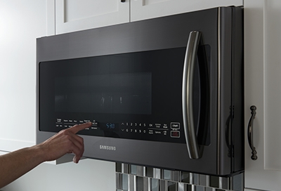 Hand pressing buttons on a Samsung over the range microwave
