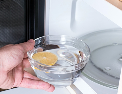 Person placing lemon water in microwave