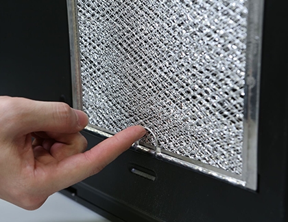 Person touching grease filter tab on Samsung microwave