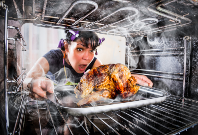 Woman removing a burnt chicken from the oven