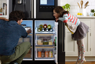 Dad and daughter looking inside a Samsung 4-Door Flex refrigerator