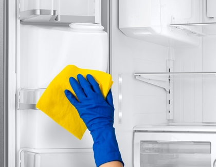 Girl wiping the fridge with yellow cloth