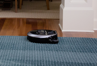 Samsung POWERbot cleaning a blue rug on a hardwood floor
