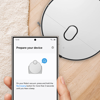 Galaxy phone showing the SmartThings app with the Samsung Jet Bot vacuum in the background