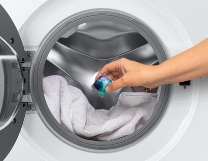 A detergent pod being placed inside of a Samsung washing machine