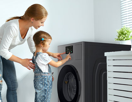 A mother and daughter touching the control panel of a Samsung washing machine