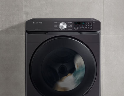 A Samsung washing machine against a gray wall.