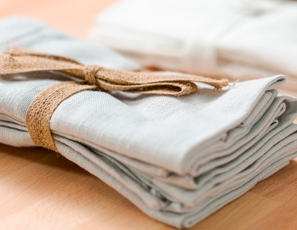 Neatly folded white tableclothes with a brown ribbon.