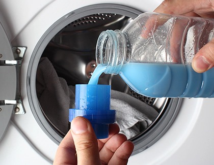A person pouring fabric softner in a cup