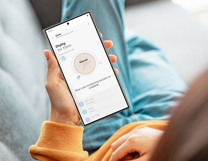A person holding a Galaxy phone while displaying a drying cycle in the SmartThings app