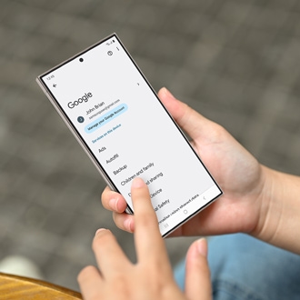 Person holding a Galaxy phone while displaying Google settings