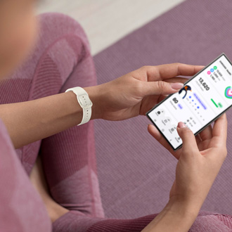 A woman holding a Galaxy S24 Ultra, showing the Samsung Health app on the screen