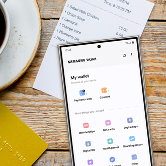 Galaxy phone next to a cup of coffee and a receipt while displaying the Samsung Wallet app