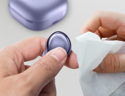 A Galaxy Buds Pro earbud being cleaned with a soft cloth.