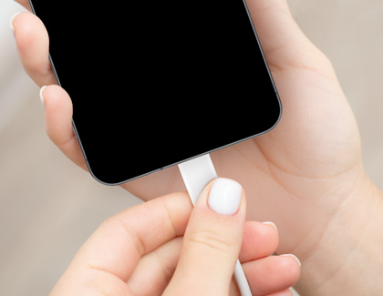 Person plugging a USB-C cable into a Galaxy A56 to charge it.