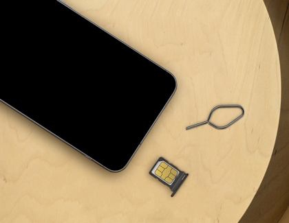 A Galaxy A56 next to a SIM card tray, SIM card, and ejector tool on a wooden surface.
