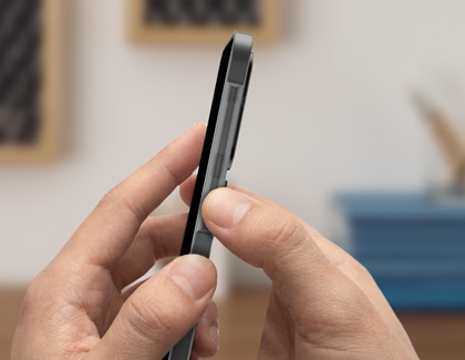 Hands holding a gray Galaxy A17 and pressing the side power button to turn the device on.